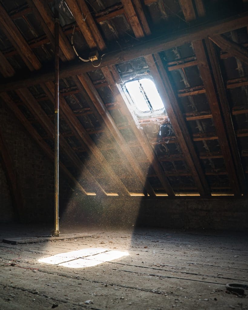 sunlight streaming through a window in a dusty, unfinished attic
