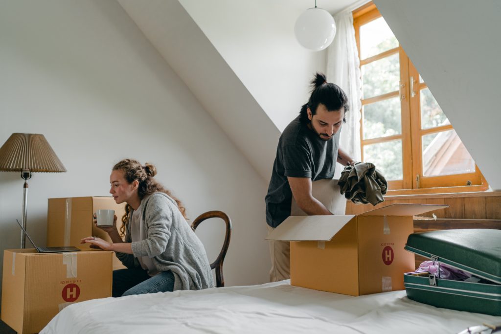Couple moving into an attic apartment, unpacking boxes near dormer window