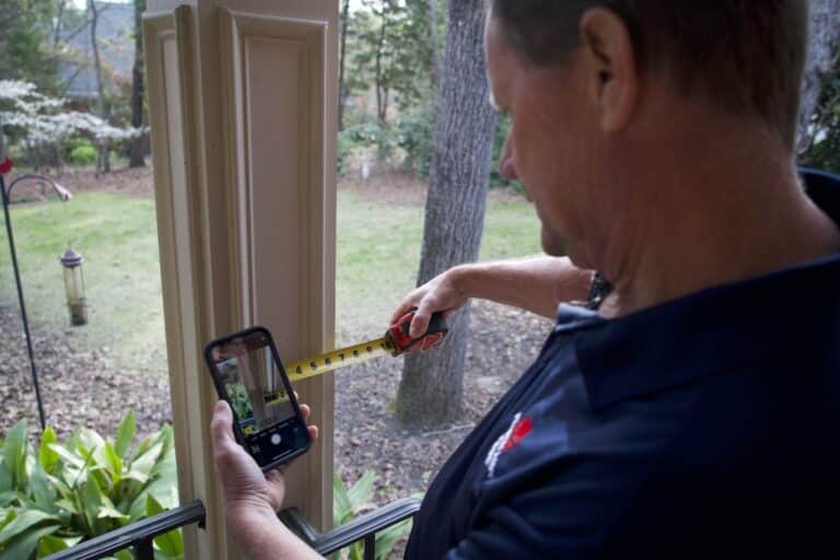 handyman measuring a porch column for a future repair