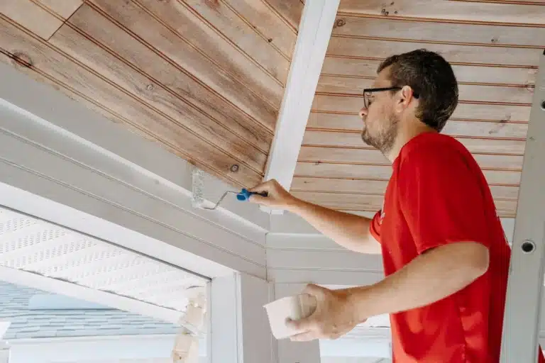 Close-up of a technician painting and staining a wooden chair, refreshing furniture with a modern finish.