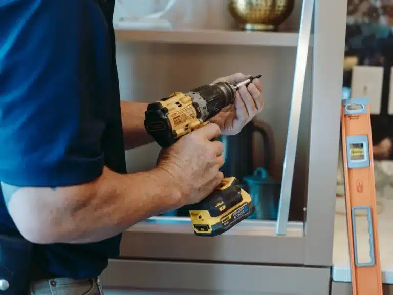 Shelving Installation 1 Worker installing floating shelves in a contemporary home office, providing practical storage and decorative display.