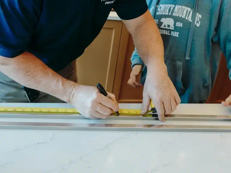 Close-up of a technician applying caulk and sealant in a kitchen, preventing water damage and ensuring a clean, finished look
