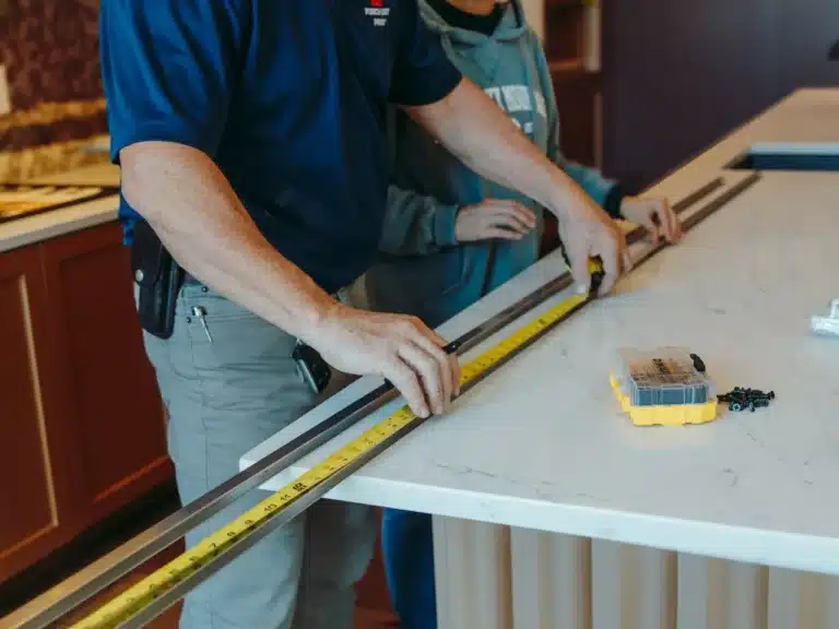 Worker repairing kitchen trim, molding, and kickplates, restoring detail and aesthetic appeal to cabinetry and walls.